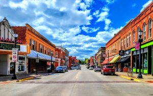 Downtown Platteville, Wisconsin on a bright, sunny day with brick red buildings and a blue sky filled with clouds.