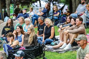 A crowd of Eau Claire, Wisconsin residents gather on blankets to watch an outdoor concert.